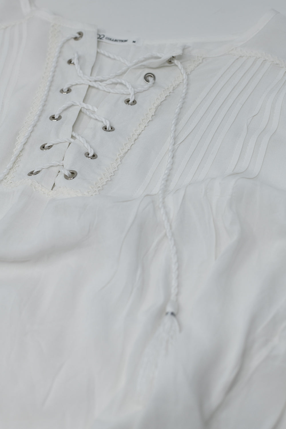 Camisa branca com pontas de borla e fecho de gravata cruzada