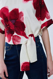 Blusa bege cortada com estampado floral tropical em vermelho atado na cintura