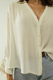 Camisa branca clara com decote em V e pormenores de riscas