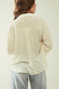 Camisa branca clara com decote em V e pormenores de riscas
