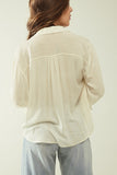 Camisa branca clara com decote em V e pormenores de riscas