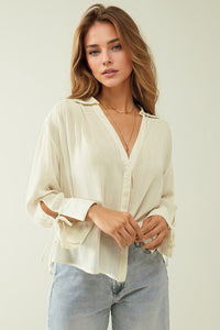Camisa branca clara com decote em V e pormenores de riscas