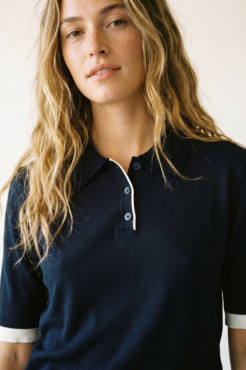 Camisa pólo azul-marinho com rebordo branco e pormenor de botões