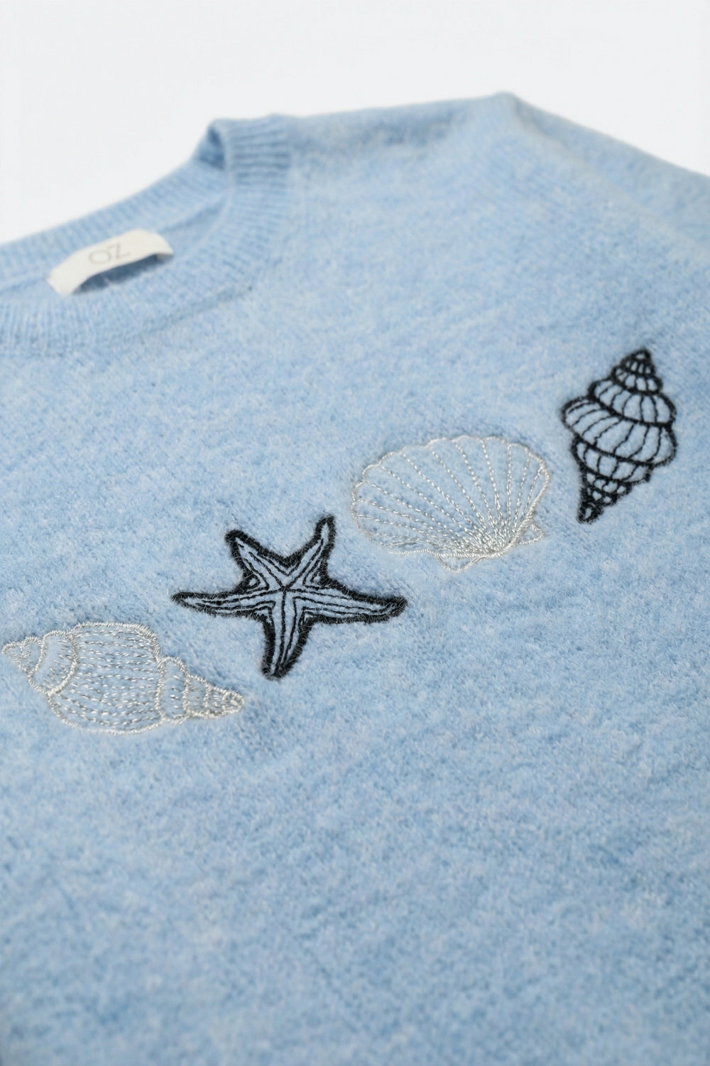 Camisola de manga curta em malha azul clara com conchas