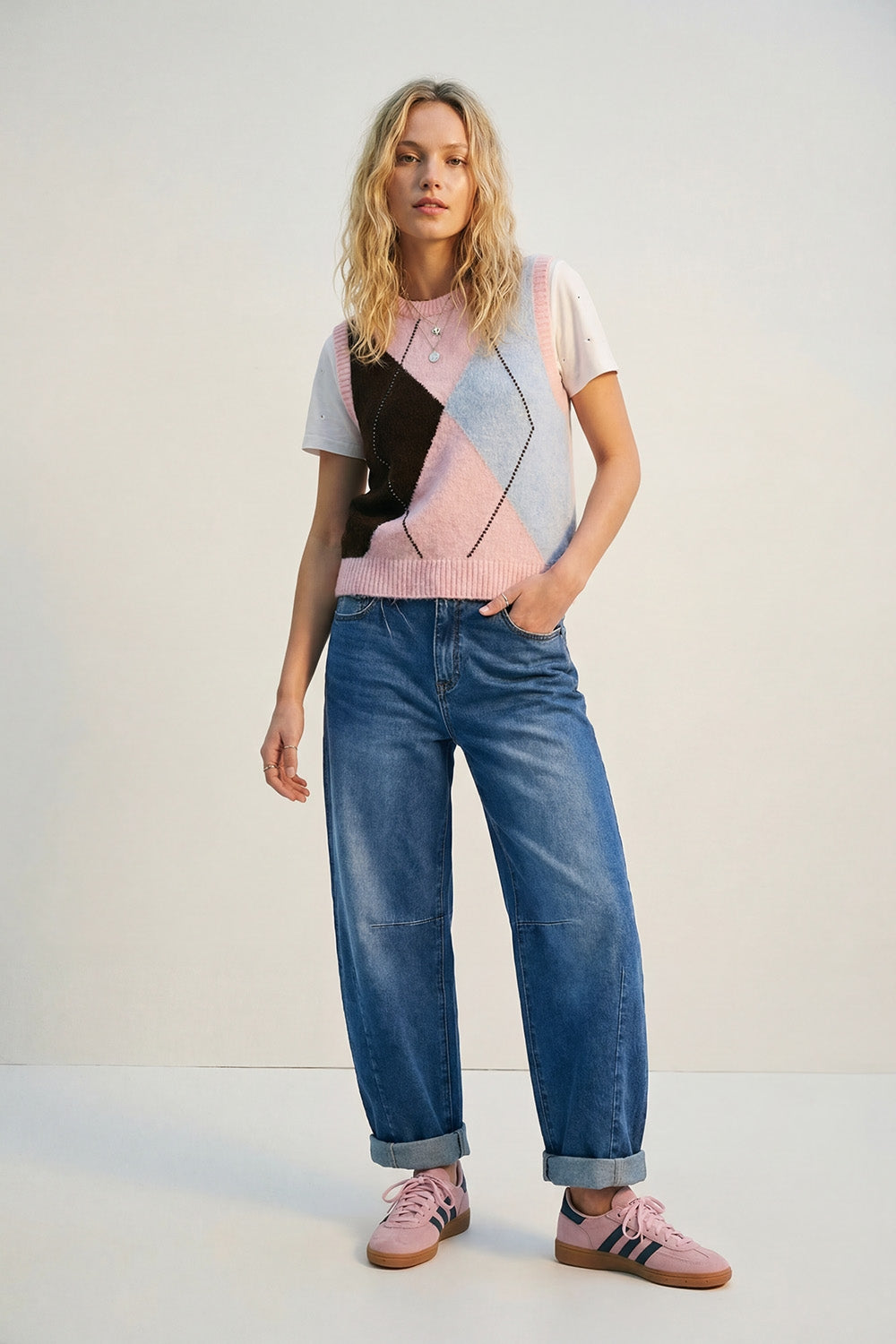 Colete de malha com estampado de losangos e detalhes de tachas metálicas em cor-de-rosa.