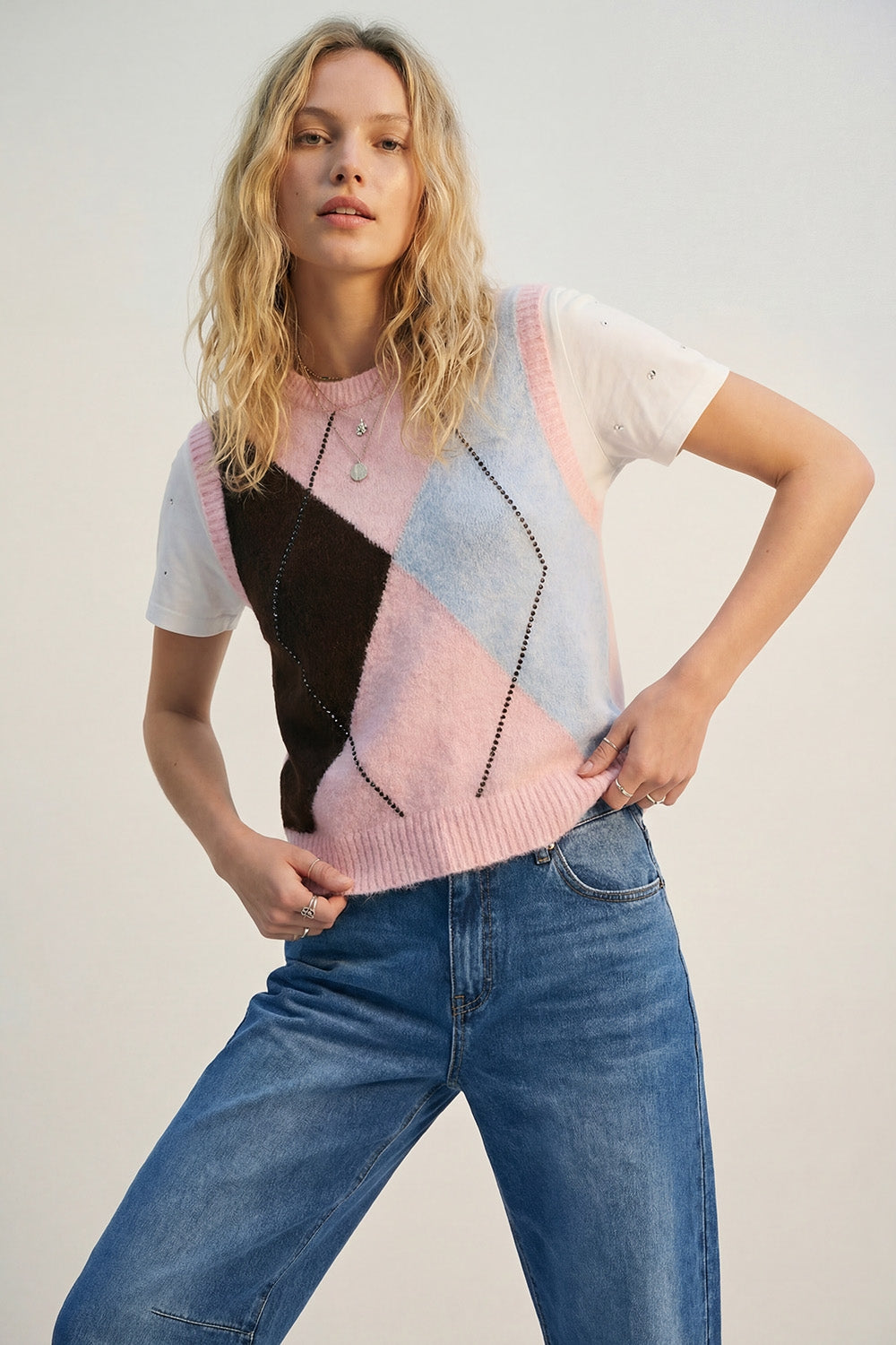 Colete de malha com estampado de losangos e detalhes de tachas metálicas em cor-de-rosa.