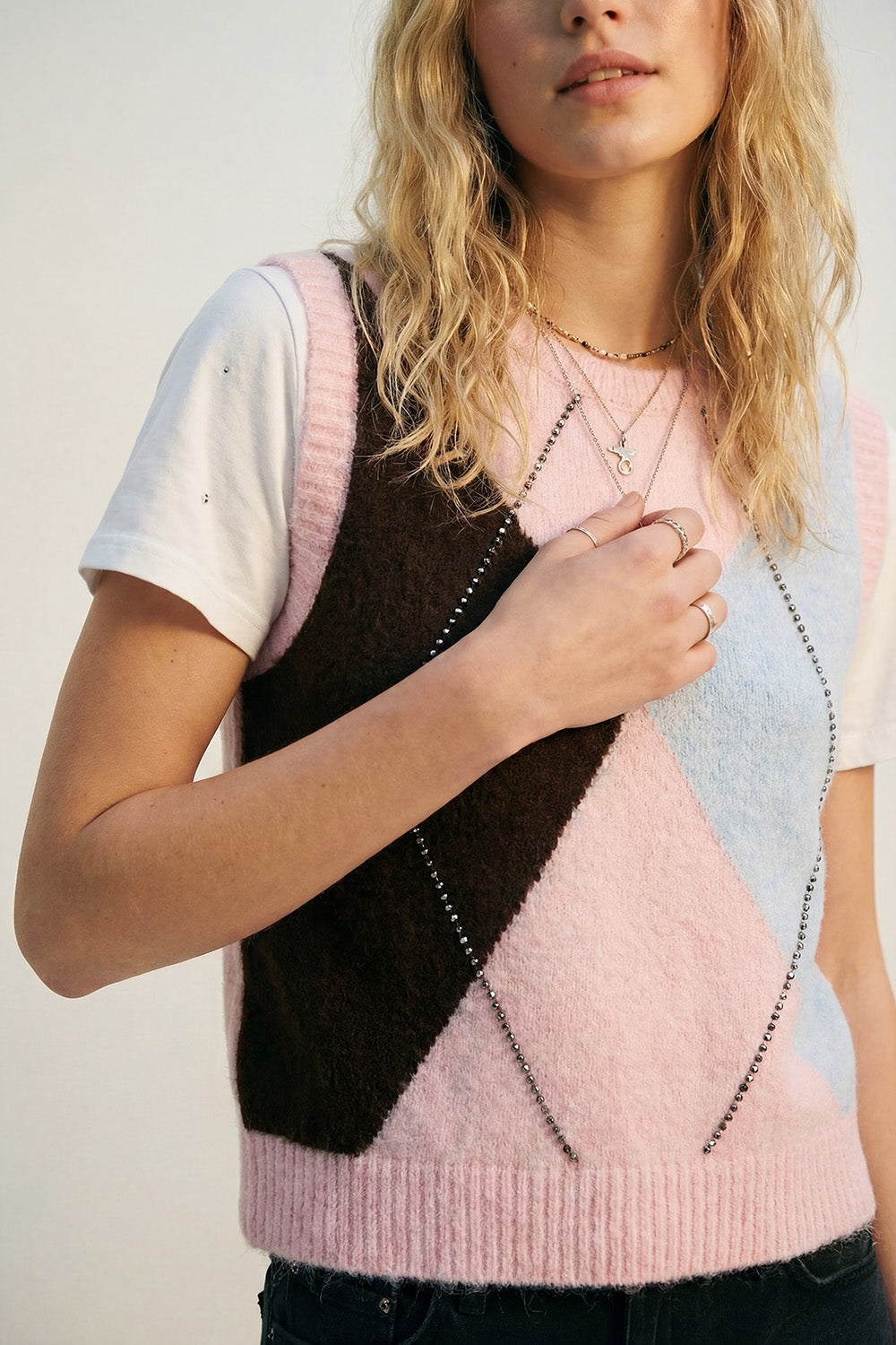 Colete de malha com estampado de losangos e detalhes de tachas metálicas em cor-de-rosa.