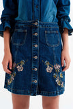 Saia jeans com flores bordadas e botões frontais