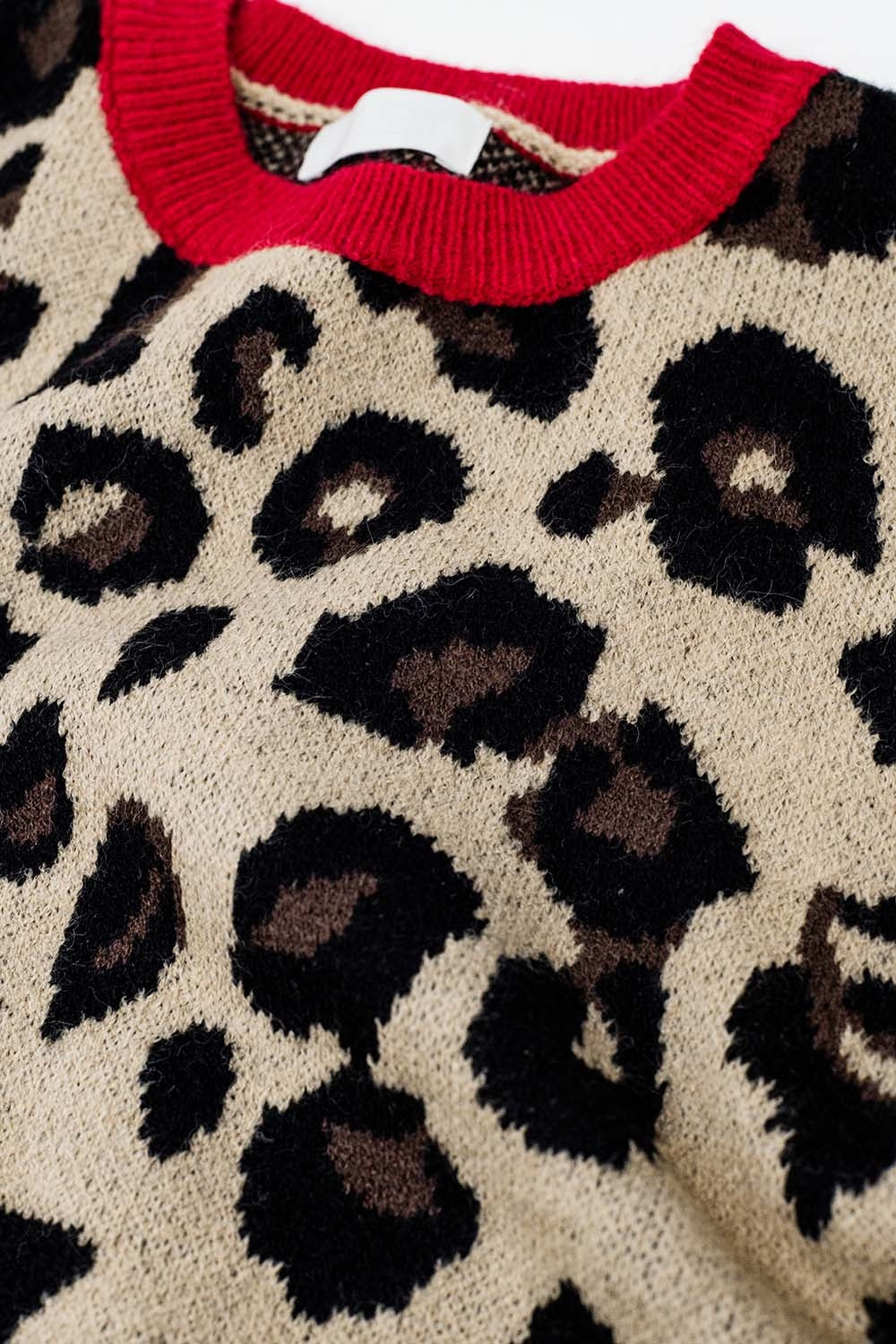 Suéter de leopardo com detalhe vermelho no pescoço e nas mangas