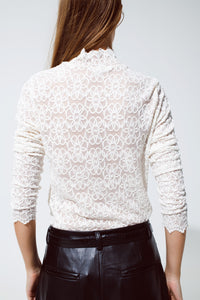 Top de gola alta com flores bordadas e pormenores de vieiras em branco